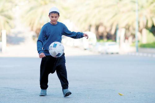 Israel: Children in Israel - Yanuh-Jat, Lower Galillee: A Druze boy playing football opposite Maqām of Sheik Shams shrine