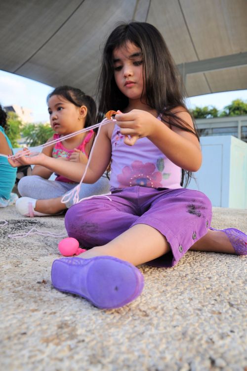 Israel: Children in Israel - Lewinsky Garden, South Tel-Aviv - Girl making a spinner with string and cardboard.